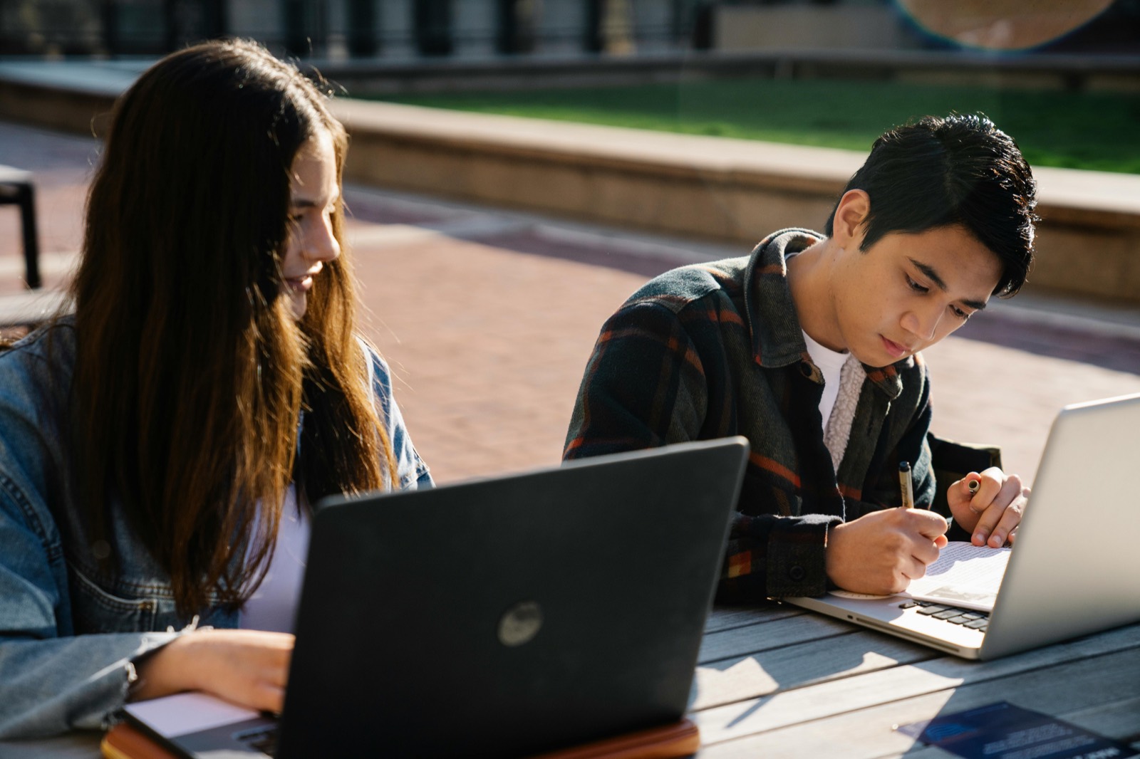 Students working together outside with laptops and notebooks